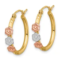 A pair of tricolor gold hoop earrings with textured rose gold and white gold flower-shaped charms arranged vertically along the yellow gold tubes.