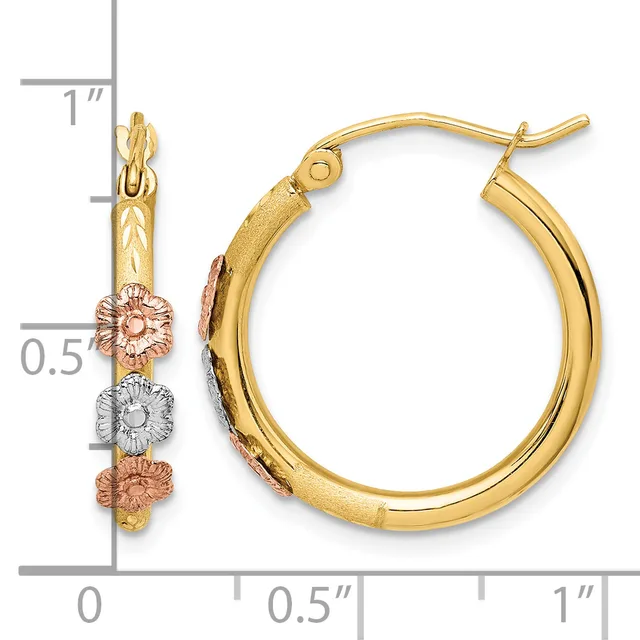 A pair of gold hoop earrings with decorative flower charms in rose and white gold, shown next to a measurement scale.