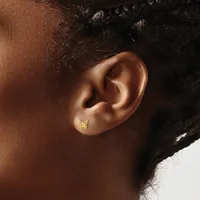A small gold butterfly stud earring worn in the earlobe of a person with brown skin and black hair pulled back.