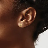 A small gold star-shaped stud earring worn in the earlobe of a person with brown skin and black hair.