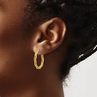 A person wearing textured gold-colored hoop earrings, shown in profile from the side of their face and neck.