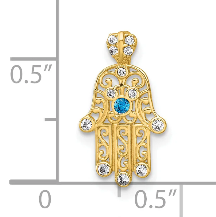 Gold hamsa hand pendant with ornate scrollwork, blue topaz center stone, and white cubic zirconia accents, shown with measurement scale indicating approximately 0.5 inches wide and 0.5 inches tall.