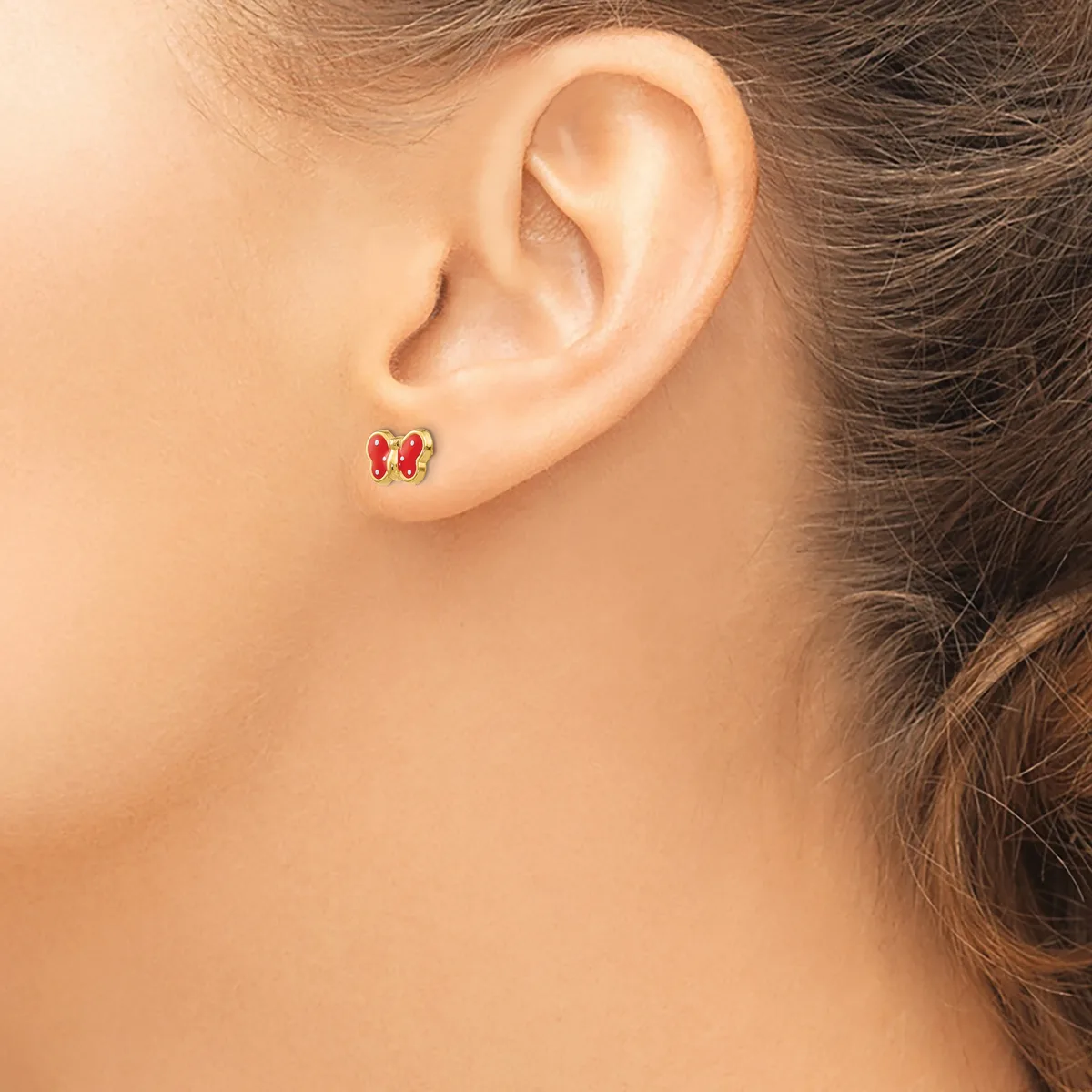 A person wearing small gold stud earrings with red gemstones, shown from the side view of their ear and neck.