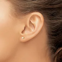 A person wearing a small pearl stud earring in their pierced earlobe, shown in profile against their shoulder and neck.