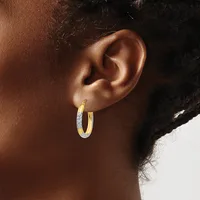 A person wearing two-toned gold and silver hoop earrings with a smooth, polished finish, shown from the side profile view.