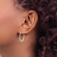 A person wearing two-tone textured hoop earrings with gold and silver finish, shown from the side profile.
