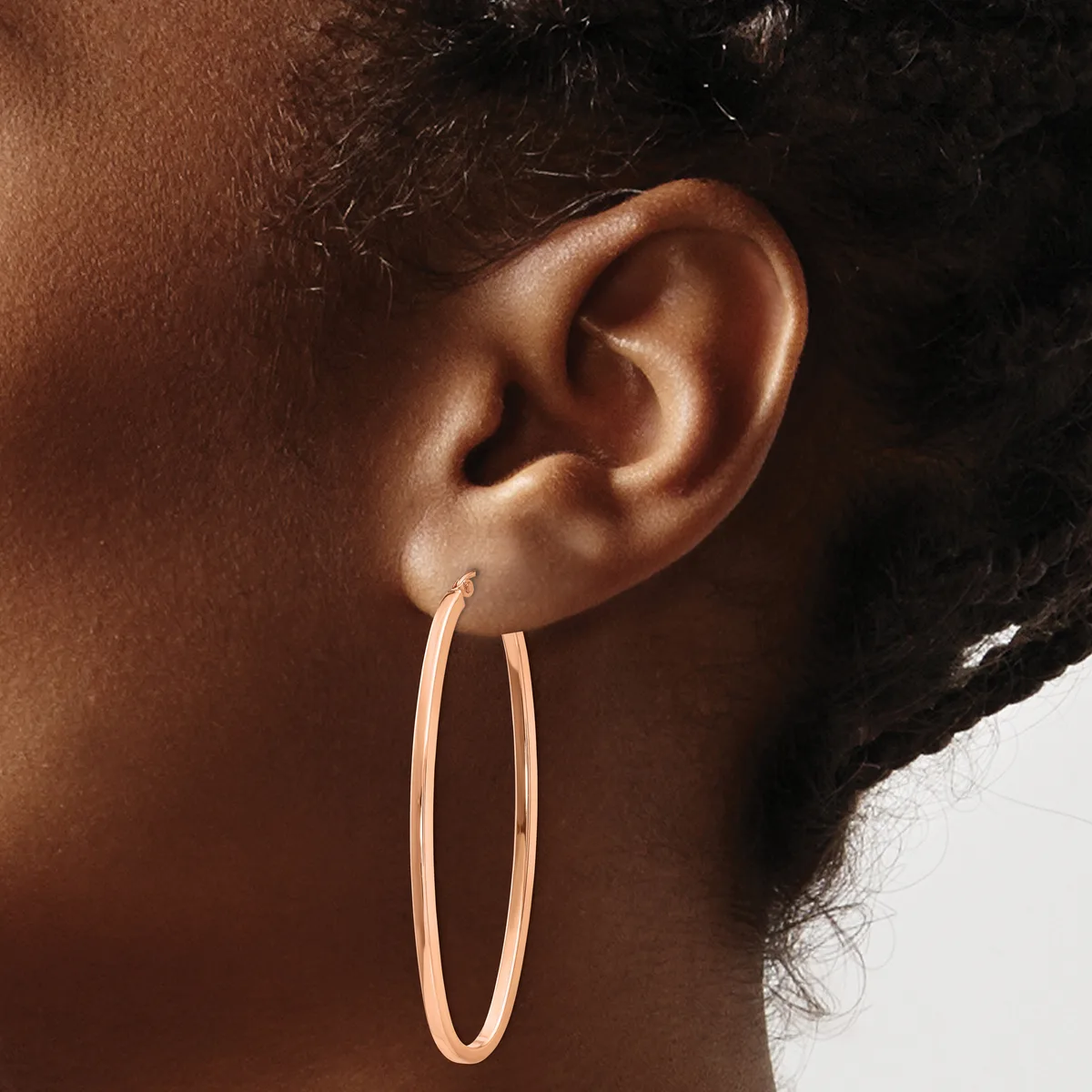 A person wearing a large rose gold oval hoop earring, shown in profile against a neutral background.