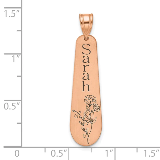 Rose gold pendant with the name "Sarah" engraved vertically and a floral design at the bottom, shown next to a measurement scale.