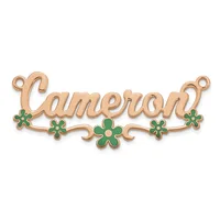 A rose gold ornament pendant with the name Cameron in script lettering, decorated with green enamel flowers along the bottom and small loops at each end for hanging.