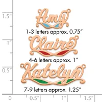 Three copper-colored name pendants with decorative flourishes and colored enamel accents, shown against a ruler measuring up to 1.5 inches.