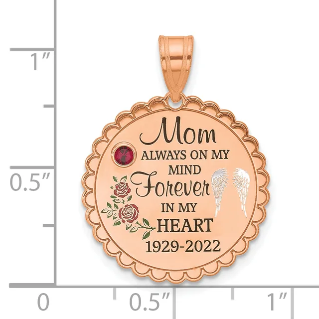 Rose gold circular pendant with scalloped edges featuring engraved text "Mom Always On My Mind Forever In My Heart 1929-2022," a ruby gemstone, roses, and angel wings, shown next to a measurement ruler.