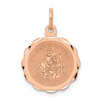 Rose gold round pendant with scalloped edges featuring Saint Christopher carrying a child, with "PROTECT US" text around the rim and a small loop bail at the top.