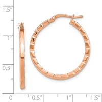 Rose gold hoop earrings with a textured segmented surface, displayed against a measurement scale showing approximately one inch in diameter.