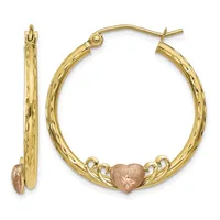 Pair of gold hoop earrings with textured surface and rose gold heart charms attached at the bottom, shown from front and side views.