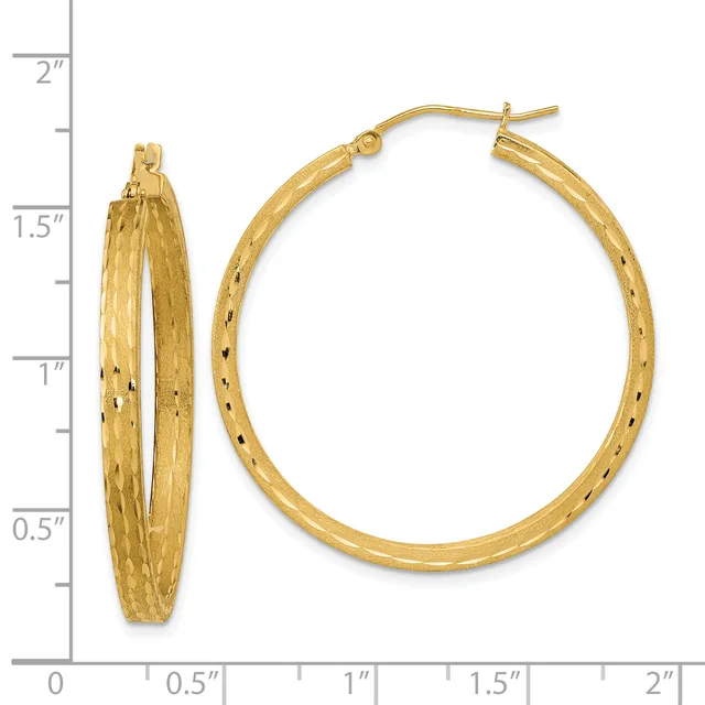 A pair of gold textured hoop earrings with a hammered finish, displayed next to a ruler showing they measure approximately 1.5 inches in diameter.