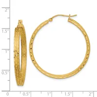 A pair of gold textured hoop earrings with a hammered finish, displayed next to a ruler showing they measure approximately 1.5 inches in diameter.
