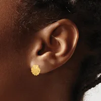 A close-up view of a person's ear wearing a small gold shell-shaped stud earring.