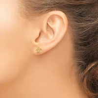 A person wearing a small gold stud earring with an ornamental design in their earlobe, shown in profile view.