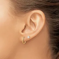 Close-up view of a person's ear wearing a small gold hoop earring and a stud earring with a round clear stone.