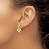 A close-up view of a person's ear wearing a gold textured drop earring with a leaf-like shape suspended from a small post.
