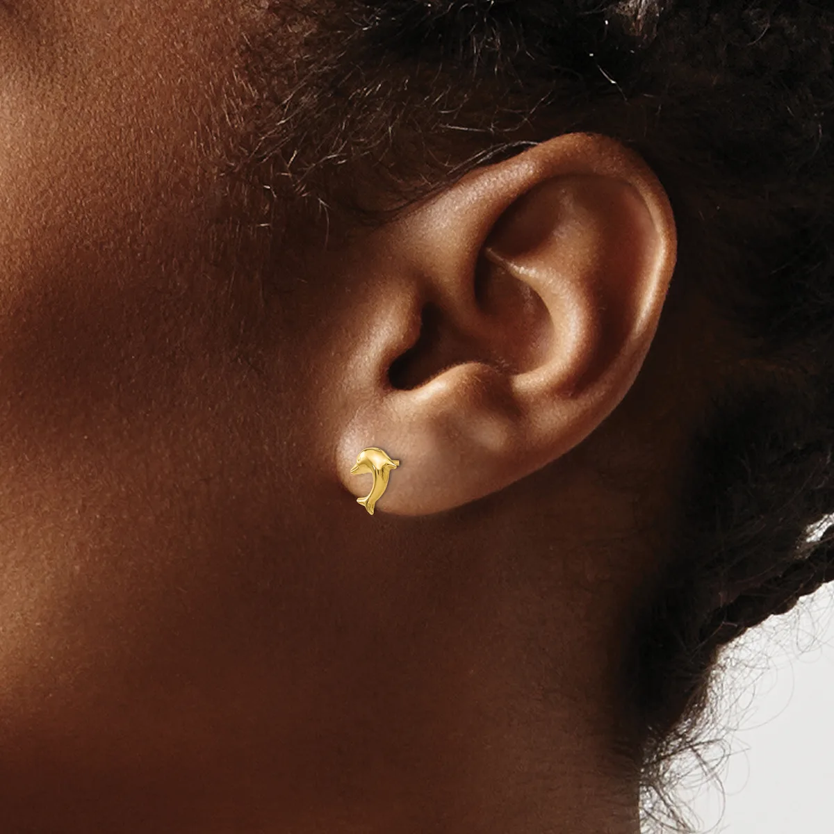 A gold curved crescent-shaped stud earring worn on the earlobe of a person shown in profile.