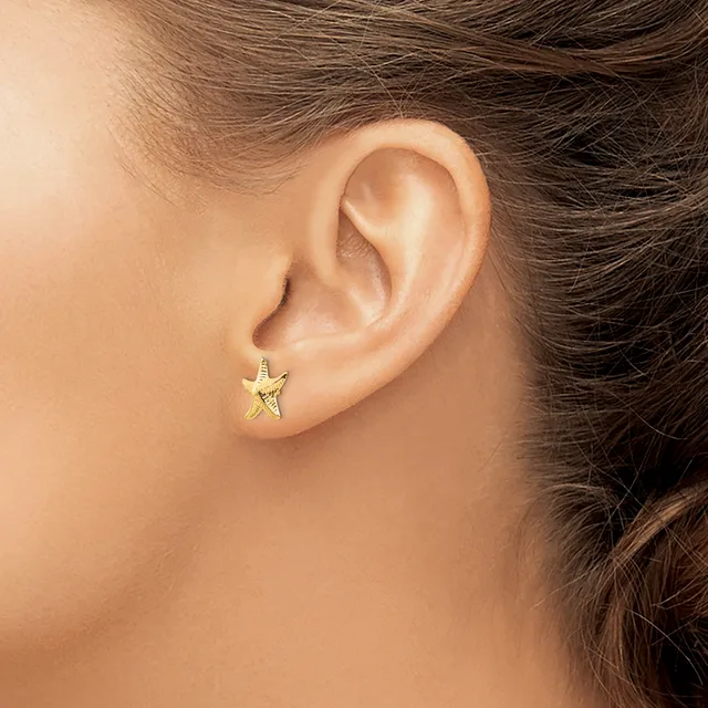 A person wearing a small gold star-shaped stud earring in their earlobe, shown in profile view.
