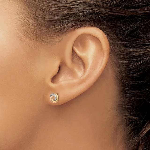 A close-up view of a person's ear wearing a small oval stud earring with a blue stone surrounded by a white metal setting.
