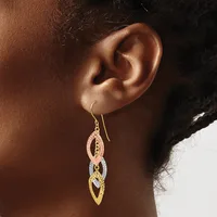 A person wearing multi-toned gold drop earrings with interlocking leaf-shaped links and textured surfaces, shown from the side profile.