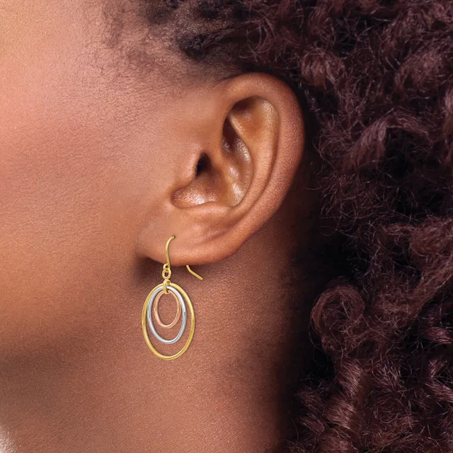 A person wearing concentric oval gold-toned drop earrings with a hook closure, shown from the side against their ear.