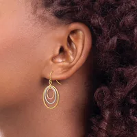 A person wearing concentric oval gold-toned drop earrings with a hook closure, shown from the side against their ear.