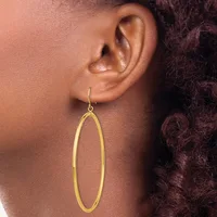A person wearing a long oval-shaped gold hoop earring hanging from a hook, shown from the side profile view.