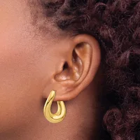 A person wearing a gold-colored curved hoop earring in their earlobe, shown in profile against their skin.