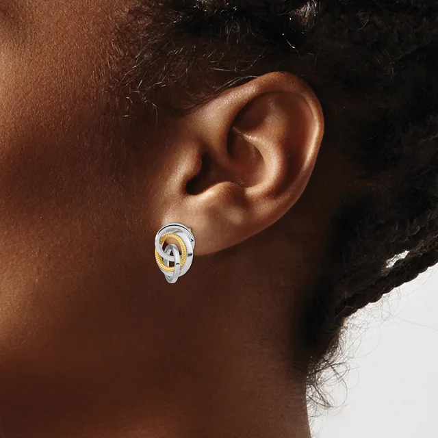 A person wearing a two-tone hoop earring with gold and silver interlocking oval links in their pierced earlobe.