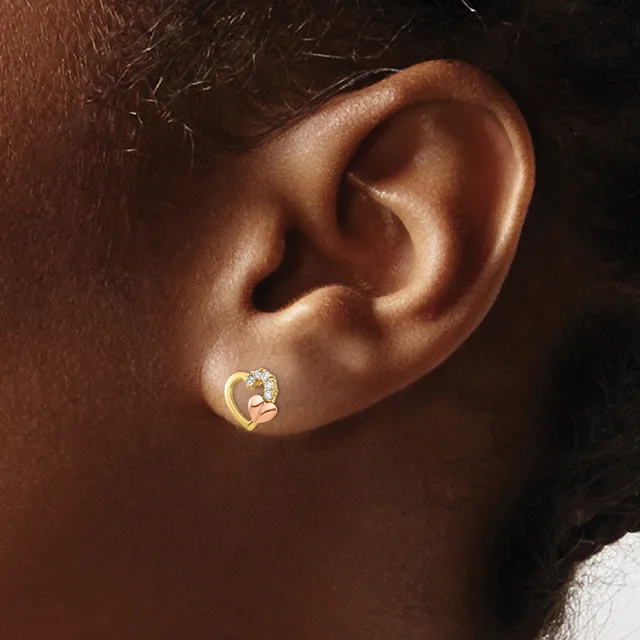 A gold curved earring with a diamond or crystal stone set in the center, worn on the earlobe of a person with brown skin.