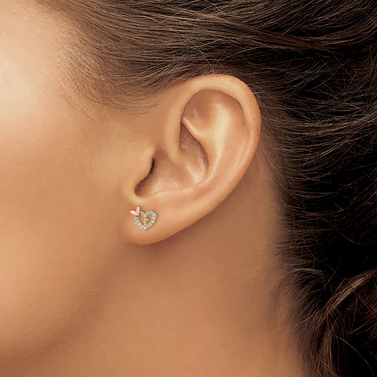 A person wearing a small heart-shaped diamond stud earring in their earlobe, shown in profile.