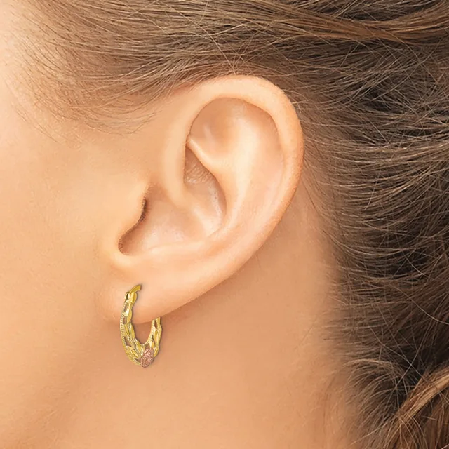 A person wearing a pair of textured gold hoop earrings with a twisted or hammered surface finish, shown from the side view of their ear.