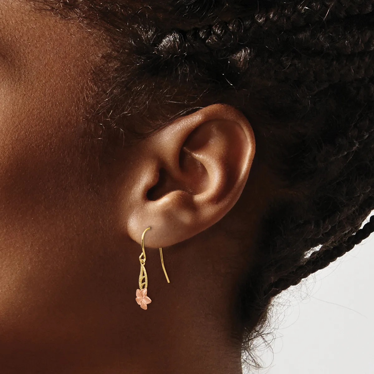 A person wearing gold-toned threader earrings with small rose quartz or pink stone pendants hanging from their pierced ears.