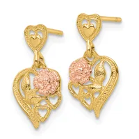 Pair of gold heart-shaped drop earrings with ornate filigree details and pink textured flower accents, shown from the front.