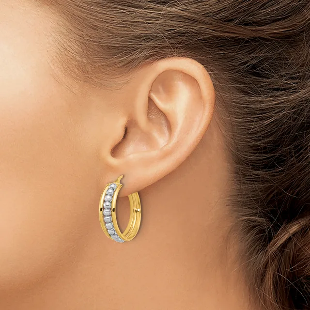 A person wearing gold hoop earrings with diamond accents on both ears, shown from the side profile.