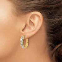 A person wearing gold hoop earrings with diamond accents on both ears, shown from the side profile.