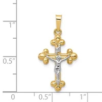 Two-tone gold crucifix pendant with white gold corpus and gold fleur-de-lis terminals, shown against a ruler measuring approximately 1 inch in height.