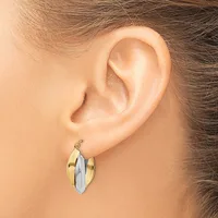 A person wearing two-tone hoop earrings with a gold outer band and silver-white center panel, shown from the side profile view of their ear.