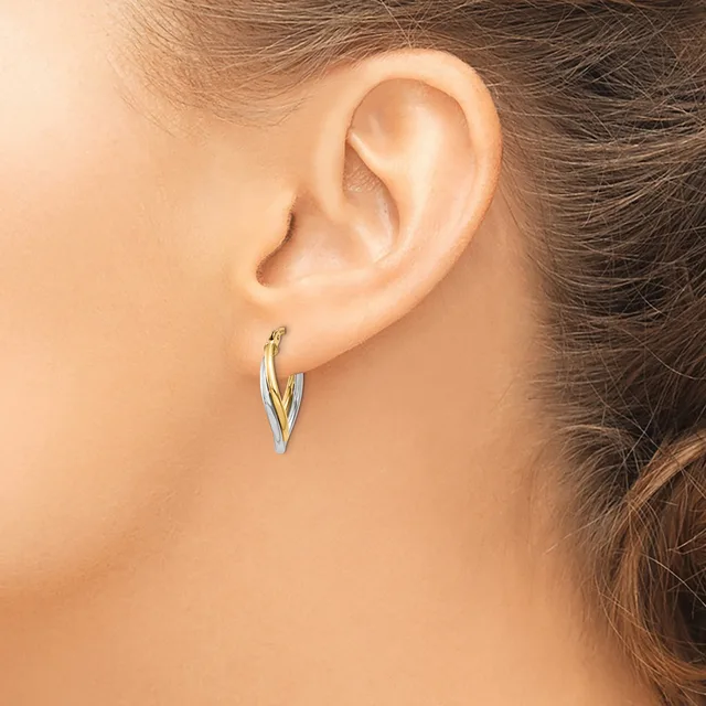 A person wearing silver-toned hoop earrings with a twisted or braided texture, shown from the side view of their ear and neck.