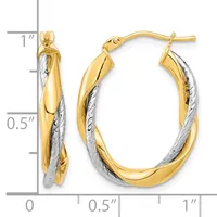 Two-tone gold twisted oval hoop earrings with yellow gold outer surfaces and white gold textured inner surfaces, displayed next to a ruler showing approximately one inch in length.