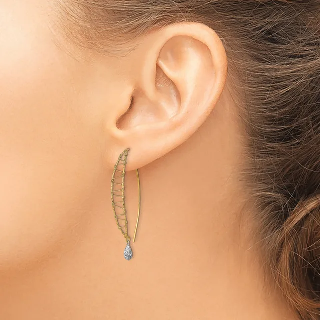 A woman wearing long silver-toned drop earrings with a teardrop crystal pendant at the end, shown from the side profile of her head and ear.