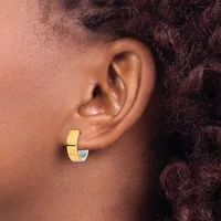 A gold hoop earring with a small diamond or crystal accent worn on the earlobe of a person with brown skin and dark curly hair.