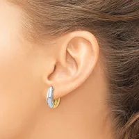 A person wearing two-tone hoop earrings with a silver outer section and gold inner section, shown from the side view of their ear.