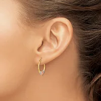 A person wearing a small gold hoop earring with colorful enamel accents on the lower portion, shown from the side view of their ear and neck.