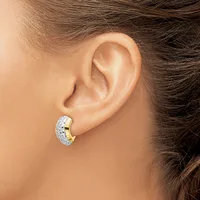 A chunky curved earring with a textured hammered finish in white metal and polished gold sections, worn on a model's earlobe.