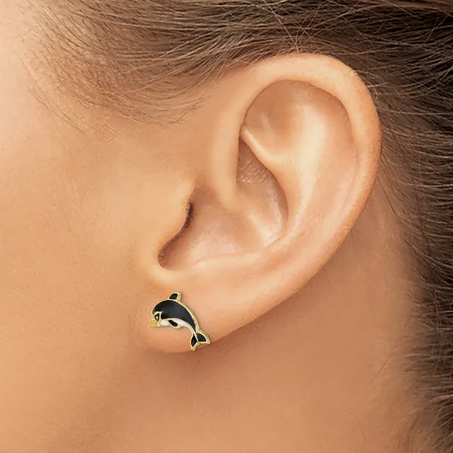 A small silver whale-shaped stud earring with black enamel detail worn in a pierced earlobe.